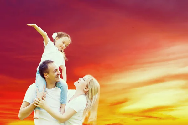 Jong gelukkig familie hebben plezier buiten, gekleed in wit en op hemel en zonsondergang — Stockfoto