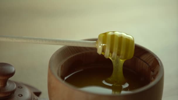 Mel com mergulhador de mel de madeira em tigela de madeira na mesa de madeira — Vídeo de Stock