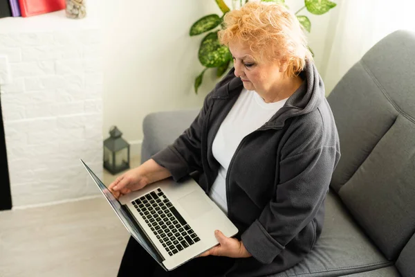Пожилая женщина смотрит на ноутбук. онлайн видео общение с родственниками — стоковое фото