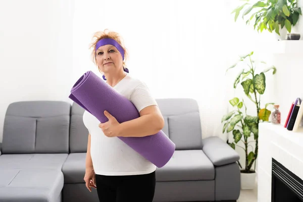 Fotografie šťastné starší ženy s podložkou na jógu po tréninku — Stock fotografie
