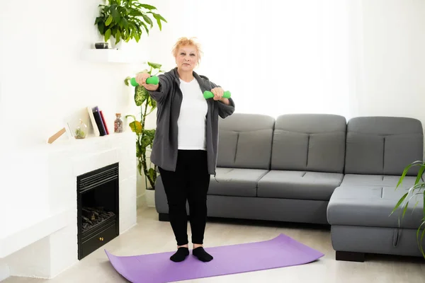 Ajuste mujer mayor feliz haciendo ejercicios de estiramiento en su esterilla de yoga — Foto de Stock