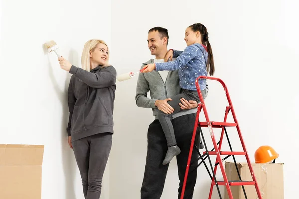 Lycklig ung familj med liten dotter målar väggen — Stockfoto