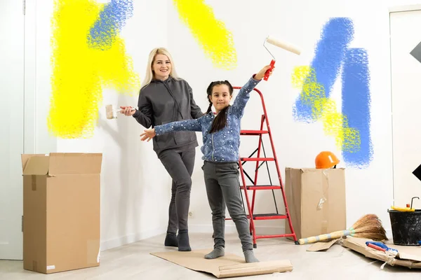 Lycklig mor och dotter gör reparationer hemma. Leende kvinna och flicka målning på väggen på rummet — Stockfoto