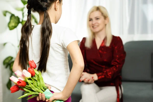 Счастливого Дня Матери. Ребенок дочь поздравляет мам и дает ей открытку и цветы тюльпаны — стоковое фото