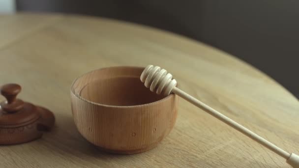 Miel con tarro de miel de madera en cuenco de madera sobre mesa de madera — Vídeo de stock