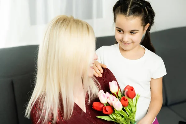Щасливий день матері. Дитяча дочка вітає мам і дарує їй листівку і квіти тюльпанів — стокове фото
