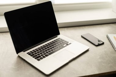 Masada dizüstü bilgisayar ve akıllı telefon, pencere kenarında iş yeri