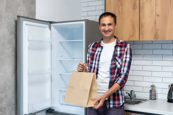Livraison, courrier et concept de personnes - homme heureux livrant de la nourriture dans un sac en papier jetable à la maison du client — Photo