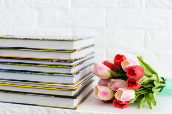 Libro de fotos y flores tulipanes como regalo de vacaciones se encuentran en el estante — Foto de Stock