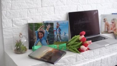 Beyaz rafta çiçekli bir dizüstü bilgisayar. laleler, fotoğraf kitabı..