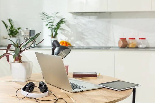 Trabalhando de casa - um computador portátil e um organizador em uma mesa de cozinha com cozinha no fundo. — Fotografia de Stock