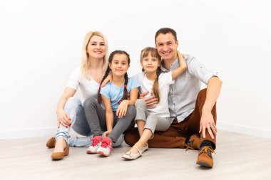 Ahşap zeminde oturan mutlu aile. Baba, anne ve çocuk birlikte eğleniyorlar. Taşınma günü, yeni ev konsepti