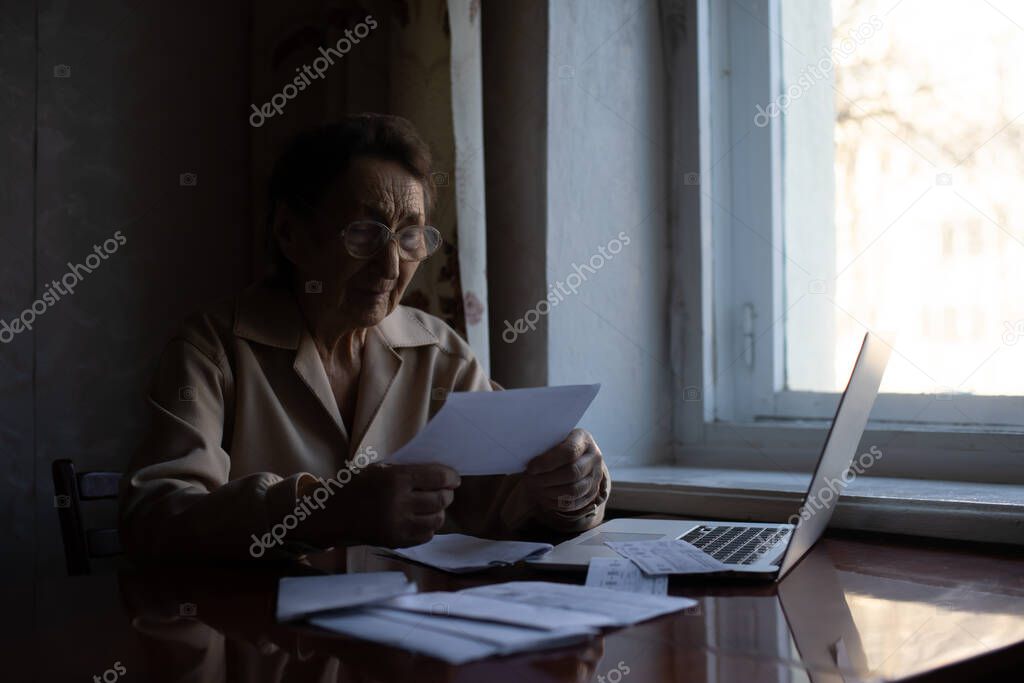 Pensioner read countless papers and is very focused. Senior woman calculating taxes at home. Retired woman calculating her domestic bills. Business, savings, annuity insurance, age and people concept