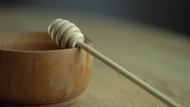 Miel en un recipiente de madera profunda, plato de madera rústica. La cuchara de madera gotea lentamente. — Vídeos de Stock