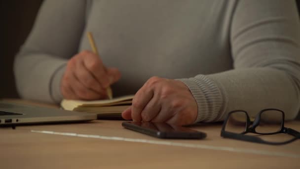 Fermer les mains masculines ridées écrivant des informations. Vieille femme mûre travaillant au bureau, à l'aide d'un ordinateur, notes manuscrites — Video