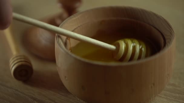 Miel con tarro de miel de madera en cuenco de madera sobre mesa de madera — Vídeos de Stock