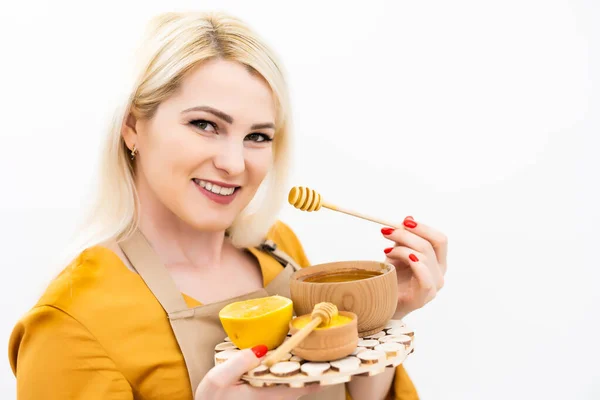 Usmívající se mladá žena s miskou medu na bílém pozadí — Stock fotografie