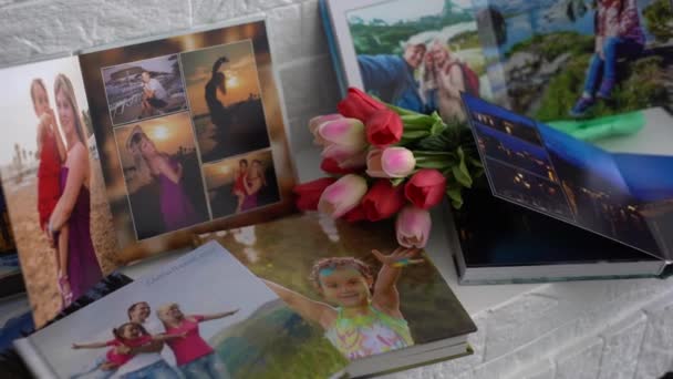 Fotobuch und Tulpen als Urlaubsgeschenk liegen im Regal — Stockvideo