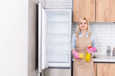 Genç kadın mutfak dolaplarını temizliyor.