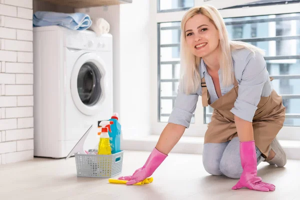 Młoda kobieta trzyma narzędzia i produkty do sprzątania w wiadrze w mieszkaniu — Zdjęcie stockowe