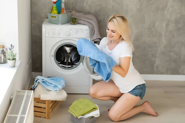 Mladá hospodyňka s pračkou a oblečením. Den praní. — Stock fotografie