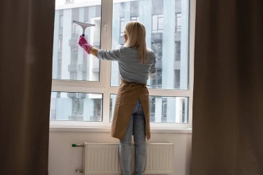 Kadın apartmanın camını temizliyor.