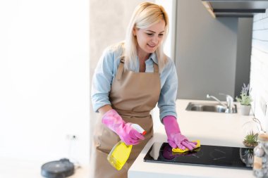 Genç bir kadın ev işi yapıyor, mutfağı temizliyor.