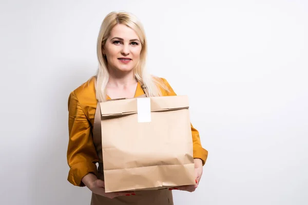 Femme donnant ordre de restauration rapide isolé sur fond blanc. Courrier féminin tenant un paquet de papier avec de la nourriture, du café. Livraison de produits du magasin ou du restaurant à la maison. Espace de copie — Photo