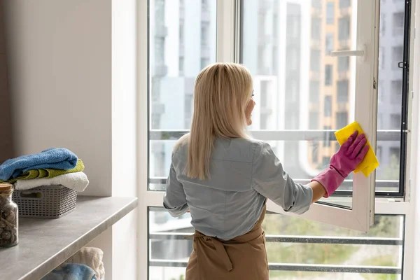 Smiling black woman cleaning windows with glass cleaner — Stock Photo, Image