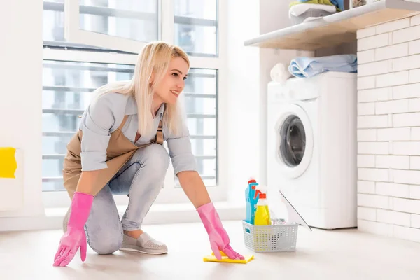 Jonge vrouw met schoonmaakmiddelen en producten in emmer in appartement — Stockfoto