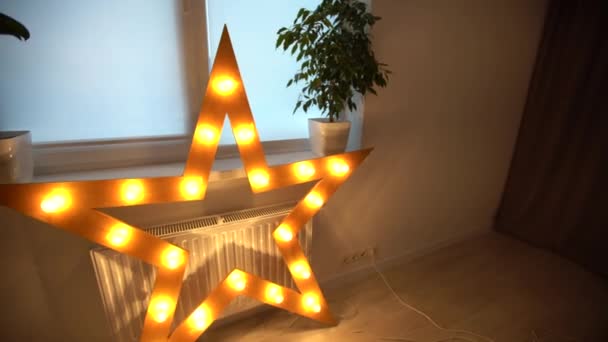 Primer plano de una sola estrella eléctrica iluminada con cálidas luces amarillas. Decoraciones de iluminación estrella en casa, celebración de Navidad y Año Nuevo en casa — Vídeo de stock