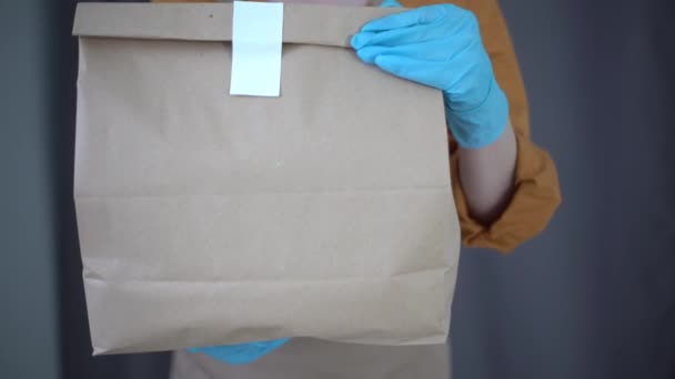 Охрана здоровья, безопасность и пандемическая концепция - доставка женщины в защитной маске и перчатках с коробкой посылки и на складском фоне — стоковое видео