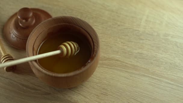 Miel con tarro de miel de madera en cuenco de madera sobre mesa de madera — Vídeos de Stock