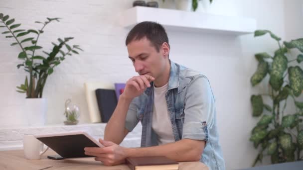 Homem trabalhando com tablet na mesa em casa, uma nova ideia veio para o homem — Vídeo de Stock