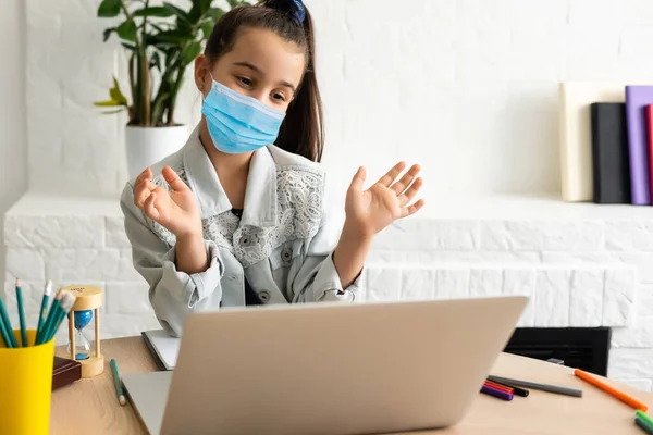Κοριτσάκι με ιατρική μάσκα που σπουδάζει στο σπίτι. επιδημία, πανδημία — Φωτογραφία Αρχείου