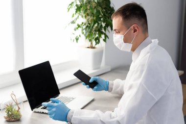 Bilgisayarlı bir erkek doktorun portresi revirde oturuyor.