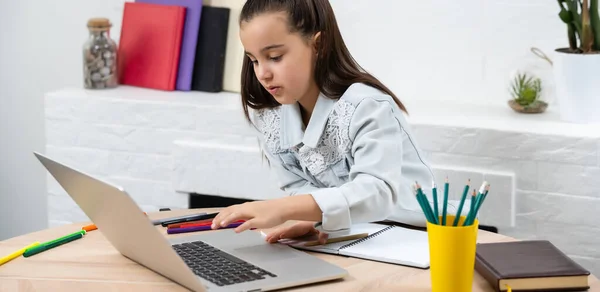 Klein meisje doet haar huiswerk thuis en met behulp van een laptop — Stockfoto