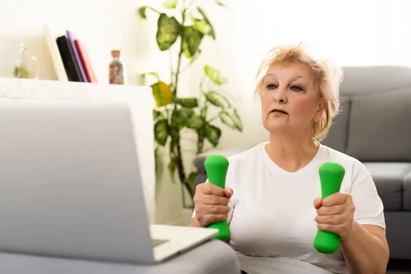 Inhemsk utbildning. Aktiva Senior Woman Making Exersise framför laptop hemma, Gratis utrymme — Stockfoto