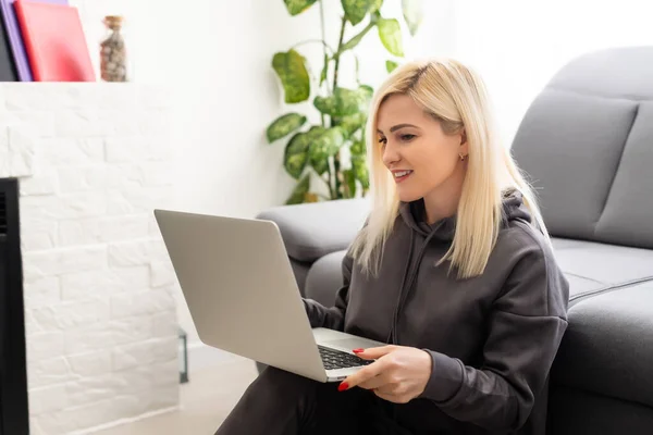 Freelancer mulher elegante positivo jovem bem sucedido está trabalhando em um laptop. Trabalho de apartamento remoto on-line. Home office atmosfera confortável. Internet empresarial — Fotografia de Stock