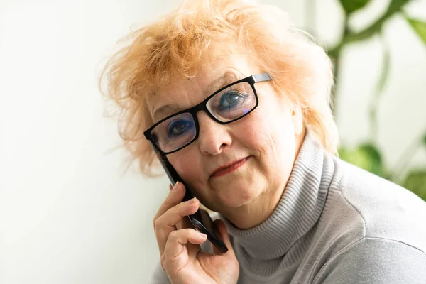 Tecnologia, età della comunicazione e concetto di persone - felice donna anziana con smartphone seduto a tavola e chiamando a casa — Foto Stock