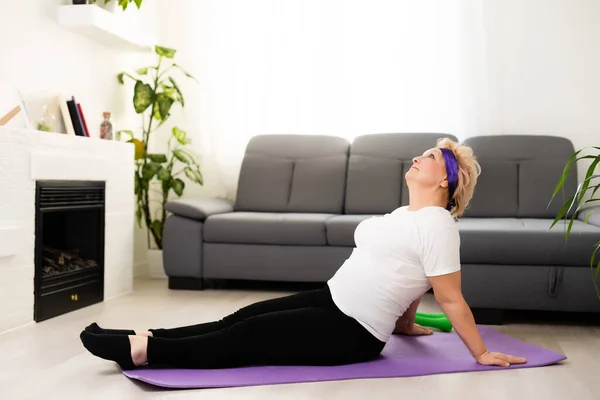 Madura mujer hace yoga lado curva — Foto de Stock