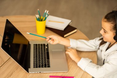 İnternette çocuk. Küçük bir kız bilgisayarda görüntülü konuşma yaparak evde otururken iletişim kuruyor..