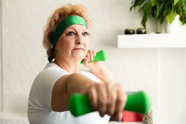 Starší žena dělá fyzická cvičení s činkou — Stock fotografie