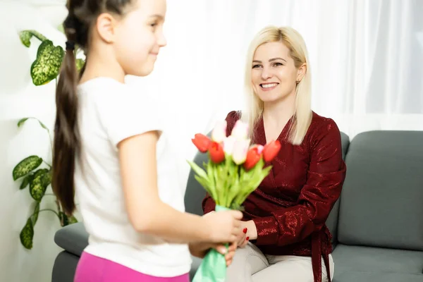 Happy mothers day. Child daughter congratulates moms and gives her a postcard and flowers tulips — Stock Photo, Image