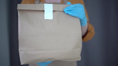 Beyaz, genç, güzel bir kadın. Teslimat işçisi sağlık maskesi. Dişi güzel kurye