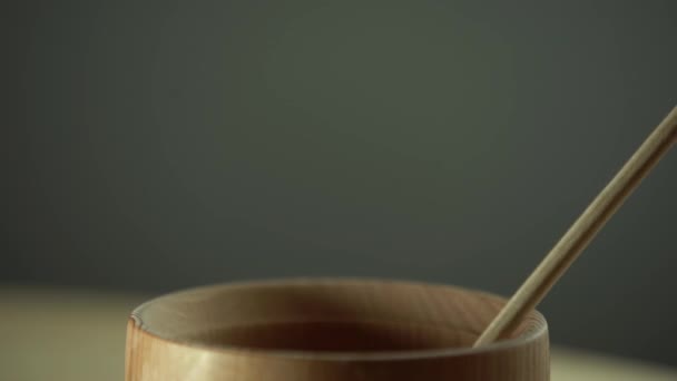 Miel con tarro de miel de madera en cuenco de madera sobre mesa de madera — Vídeo de stock