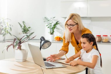 Coronavirus salgını. Kilitlenme ve okul kapanır. Anne, kızının evde online ders çalışmasına yardım ediyor. COVID-19 salgını, çocuklar ve öğretmenler çevrimiçi öğrenim.