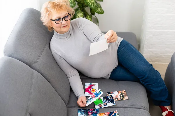 En äldre kvinna tittar på ett foto av sina barnbarn — Stockfoto