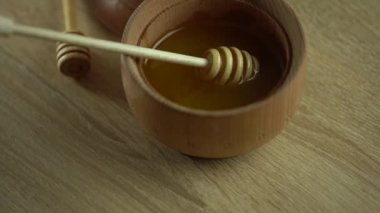 Bal damlıyor, ahşap kaseye bal damlatıyor. Yakın plan. Ahşap bal kaşığından batırılan sağlıklı organik bal, yakın plan. 4K UHD video görüntüleri. Yavaş çekim