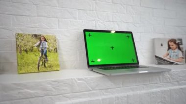 Ev işi masasında masa lambasının yanında duran yeşil ekran dizüstü bilgisayar..